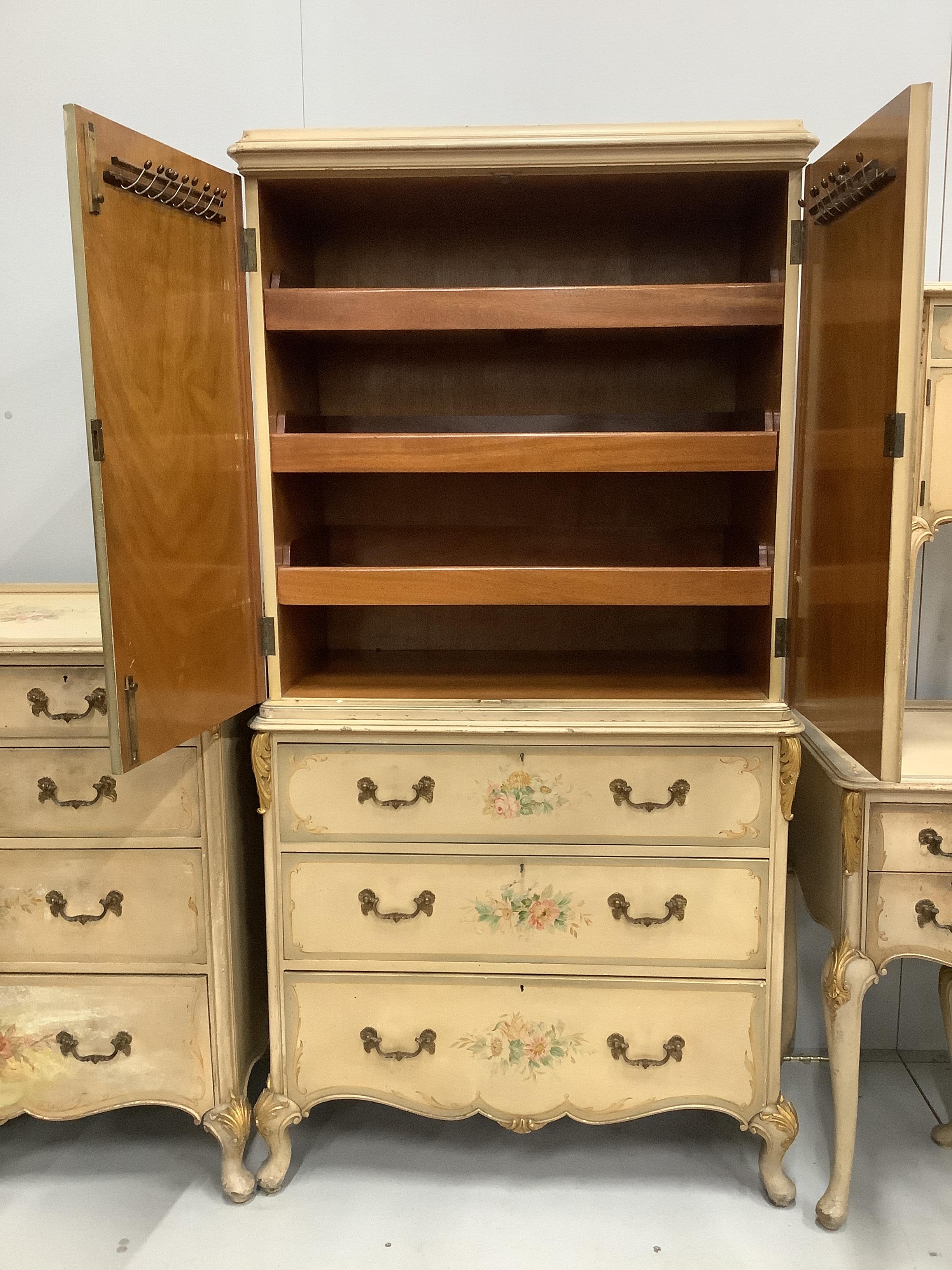An 18th century style painted seven piece bedroom suite, comprising press cupboard, pair of bedside cabinets, kneehole dressing table, stool, chest of drawers and tub framed side chair